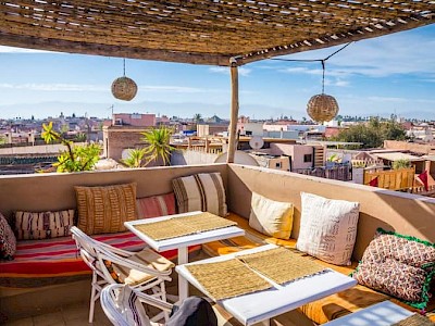 Dakterras met gekleurde kussentjes en uitzicht over Marrakech in Marokko